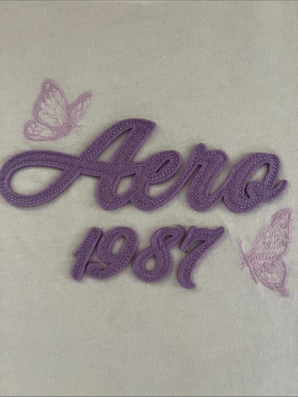 1987 Women’s White Graphic Tee with Purple Script